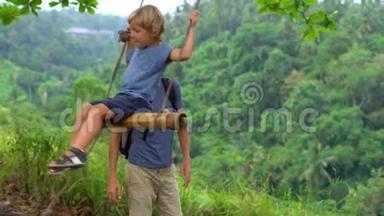 一个年轻人在热带公园的<strong>秋千</strong>上摆动他的小儿子的慢镜头。 <strong>儿童</strong>概念